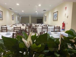 uma sala de jantar com mesas brancas, cadeiras e plantas em Angelus em Fátima