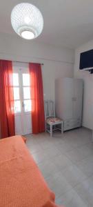 AnalipsiにあるFilina's Studioのベッドルーム(オレンジ色のベッド、赤いカーテン付)