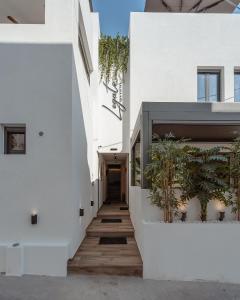 a hallway of a white building with plants at Legato Spa Suites in Naxos Chora