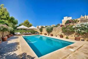 a swimming pool in a villa with a stone wall at Casa Mezzodì' - Luxurious 18th C. Farmhouse with Gardens & Pool in Kerċem