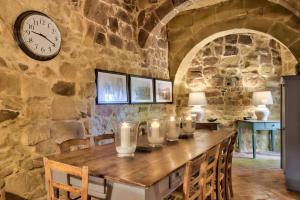 comedor con mesa y reloj en la pared en Casa Mezzodì' - Luxurious 18th C. Farmhouse with Gardens & Pool, en Kerċem