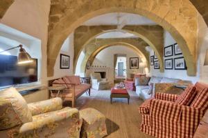a living room with a stone archway with couches at Casa Mezzodì' - Luxurious 18th C. Farmhouse with Gardens & Pool in Kerċem
