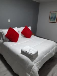 Una cama con almohadas rojas y blancas. en HOTEL SUAREL CENTER, en Duitama