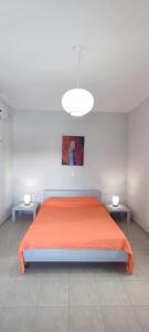 1 dormitorio con 1 cama grande de color naranja y 2 mesas en Filina's Studio, en Maltezana