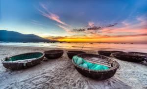 3 Boote sitzen bei Sonnenuntergang am Strand in der Unterkunft Thanh Hiền HB Hotel in Đà Nẵng