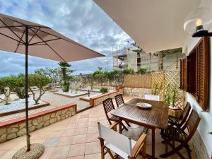 un patio con tavolo e sedie in legno e ombrellone di Casa Perla Marina sul mare a Castellammare del Golfo