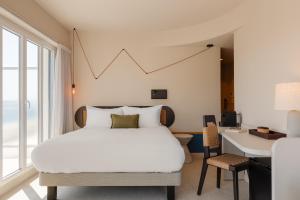 1 dormitorio con cama blanca, escritorio y ventana en Yelo Promenade powered by Sonder, en Niza