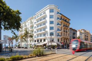 een rode tram op een straat voor een gebouw bij Yelo Promenade powered by Sonder in Nice