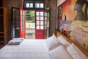1 dormitorio con cama blanca y puerta roja en Lobie Armazém São Joaquim, en Río de Janeiro