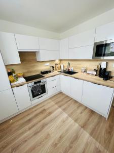 una cucina con armadietti bianchi e pavimenti in legno di KOBRA Apartment a Moravská Ostrava