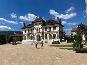 two people walking in front of a large building at Cazare David si familia . in Piatra Neamţ