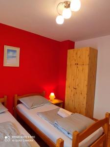 バニョレにあるMaya balcony apartmentの赤い壁のベッドルーム1室、ツインベッド2台が備わります。