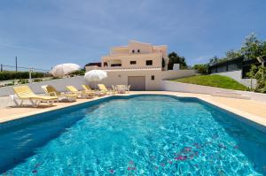 a swimming pool with chairs and a house at Villa Larotil in Lagoa