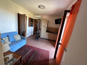 uma sala de estar com um sofá azul e uma cozinha em B&B Casale Roshlee em Gualdo Cattaneo