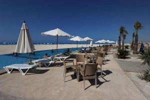 a row of chairs and umbrellas on a beach at Luxury Chalet With Roof at Nice 4 North coast kilo 75 نيس ٤ in Dawwār Abū Duray‘ah ‘Abd al Karīm