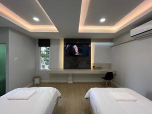 a room with two beds and a tv on the wall at The leaf mango tree in Kamphaeng Phet