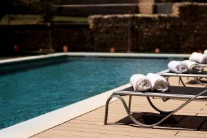 a pool with two lounge chairs next to a swimming pool at Hotel Pax Guadalajara in Guadalajara