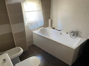 een badkamer met een wit bad en een toilet bij Sweet Home in Moaña