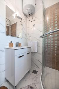 a white bathroom with a shower and a sink at Apartments MENA in Bibinje