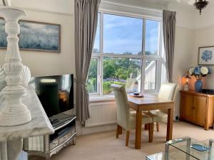 a living room with a table and a large window at The KinBrae Apartment in Torquay