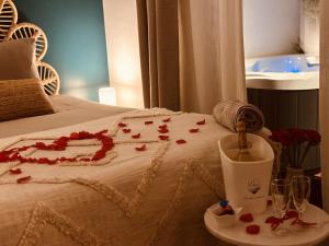 una cama con pétalos de rosa roja con una vela en Loft cosy Menorca 5 étoiles Spa au cœur de Nancy, en Nancy