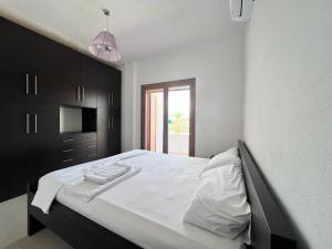 a bedroom with a large bed with white sheets and a window at Roel House in Sarandë