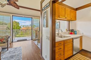 una cucina con lavandino e una porta che conduce a un balcone di Beautiful Poipu AC, Walk to Beach, Pool and Tennis KP117 a Koloa