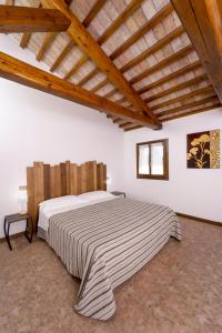 una camera con un grande letto in una stanza con soffitti in legno di La Tenuta Va Oltre a Bovolenta