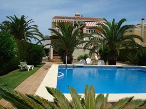 a swimming pool with palm trees and a building at Casa Hermosa in Oliva