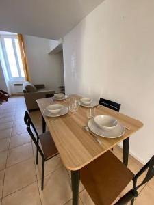 a wooden table with chairs and plates and glasses on it at Grand appartement jardins de la Fontaine in Nîmes