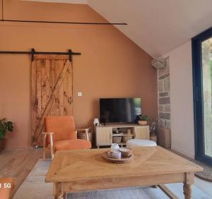 - un salon avec une table en bois et une télévision dans l'établissement La Bergerie, à Évellys