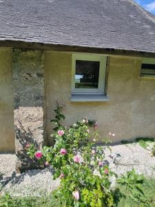 un bâtiment avec une fenêtre et des fleurs devant lui dans l'établissement La Bergerie, à Évellys