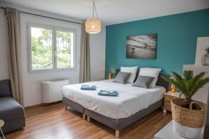 a bedroom with a large bed and a blue wall at Ocean Garden Surf Lodge in Capbreton