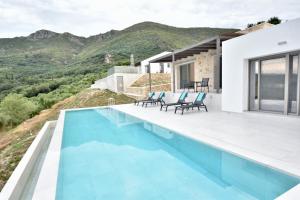 a villa with a swimming pool with mountains in the background at Blue Lilac Villas in Parga