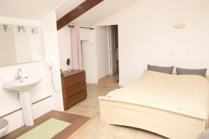 a white bedroom with a large bed and a sink at Maison avec jardin centre historique in Agde