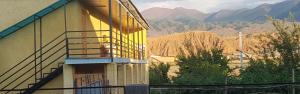 a yellow building with a balcony with mountains in the background at " UMAR " Guest house in Tong