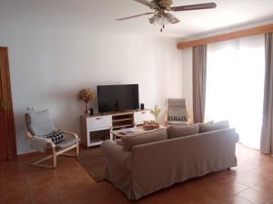 ein Wohnzimmer mit einem Sofa und einem Flachbild-TV in der Unterkunft Casa Rural El Algarrobo in Utrera