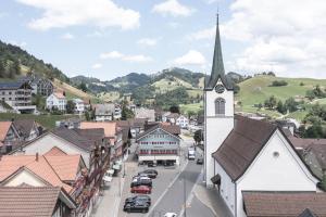 a small town with a church and a street with cars at Dorfplatz Urnäsch in Urnäsch