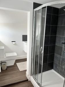 ein Bad mit einer Dusche mit schwarzen Fliesen in der Unterkunft Ground floor flat in Keynsham