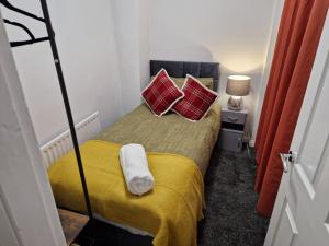 a small bedroom with a bed with two red pillows at Chester Le Street's Emerald 3 Bed House in Chester-le-Street