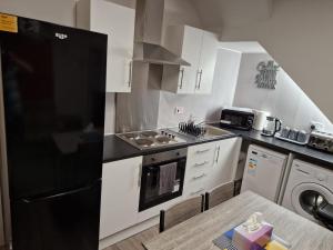a kitchen with white cabinets and a black refrigerator at Chester Le Street's Emerald 3 Bed House in Chester-le-Street