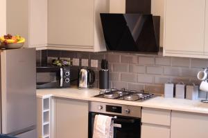 a kitchen with a stove and a microwave at Sandbach Apartments in Sandbach