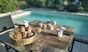 a picnic table with a basket of bread and a laptop at La Maison Bleue Normande in Maniquerville