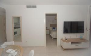 uma sala de estar branca com uma televisão e uma mesa em Topacio 3 en prim43ra linea de la playa en Calpe con Buenas vistas em Calpe