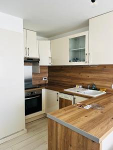 cocina con armarios blancos y encimera de madera en RAINIE APPART en Palavas-les-Flots