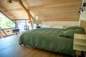 um quarto com uma cama verde num quarto com tectos em madeira em Chalet d'Andreyt em Béost