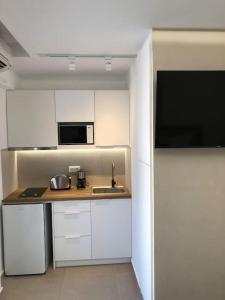 a kitchen with white cabinets and a sink and a microwave at Anastasia Suite/byArtistUnknown in Vari