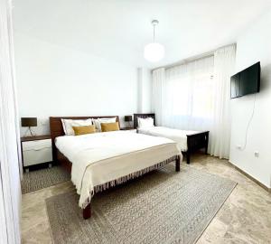 a white bedroom with two beds and a tv at Los Naranjos close to Puerto Banus in Marbella