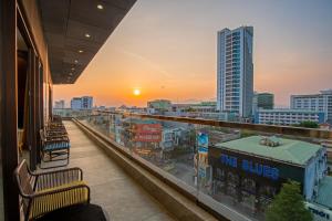 einen Balkon mit Blick auf eine Stadt bei Sonnenuntergang in der Unterkunft G8 Luxury Hotel and Spa Da Nang in Đà Nẵng