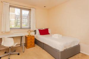 a bedroom with a desk and a bed with a red pillow at Homely 3 Bedroom House with a Garden in London